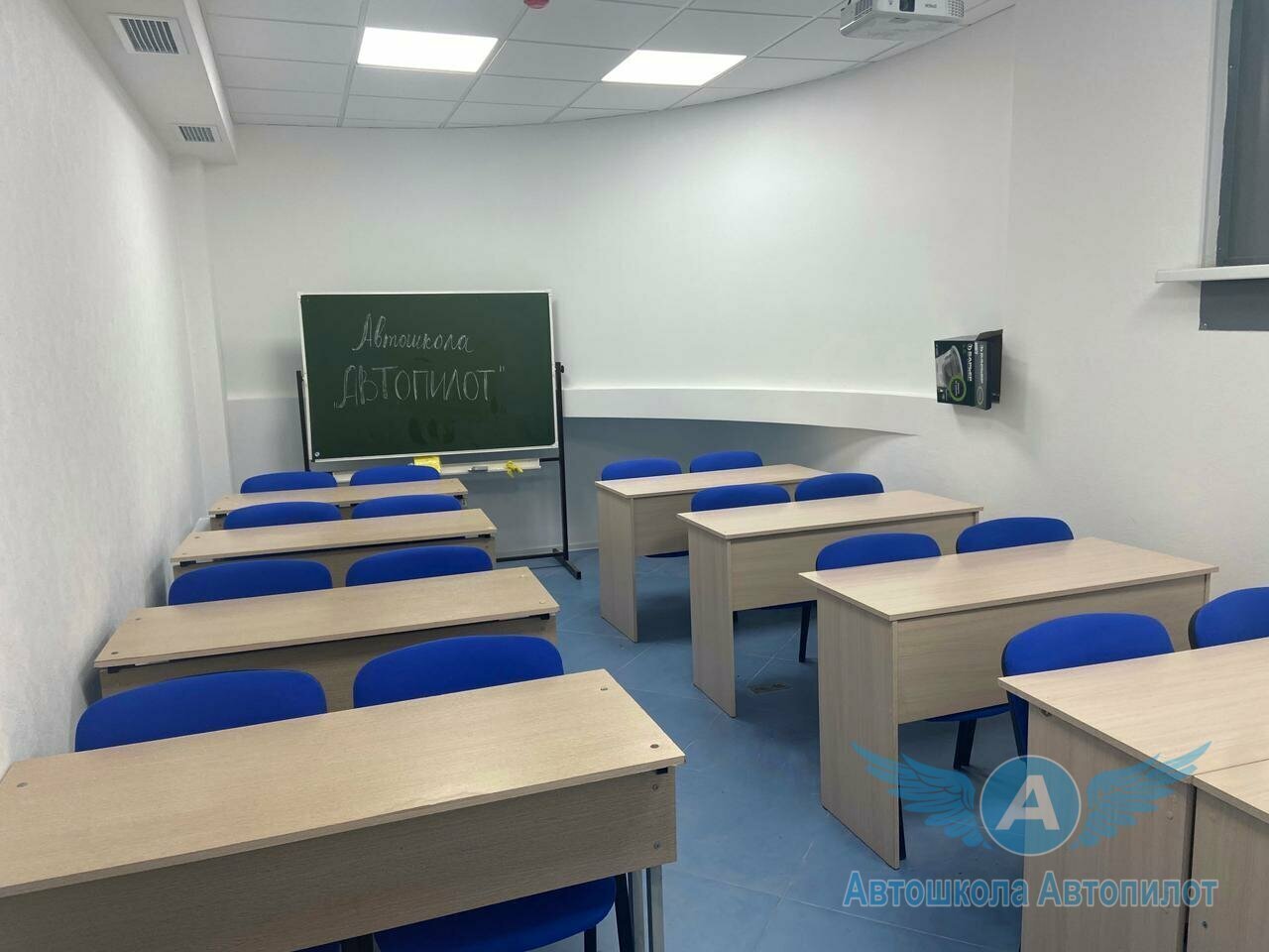 Класс автошколы «Автопилот» с партами, синими стульями и доской